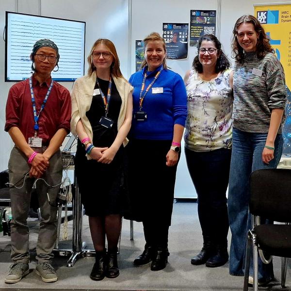 four people stand in front of the stand