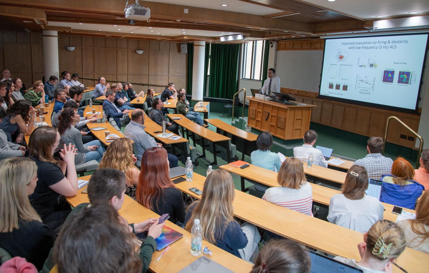 A photo of Karunesh Ganguli and audience at the Unit’s Science Day in Summer 2024.